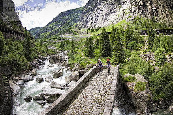 Zwei Mountainbiker üerqueren eine Brücke  Andermatt  Schweiz