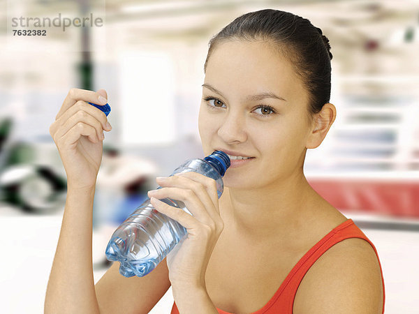 Frau mit Wasserflasche im Fitnessstudio