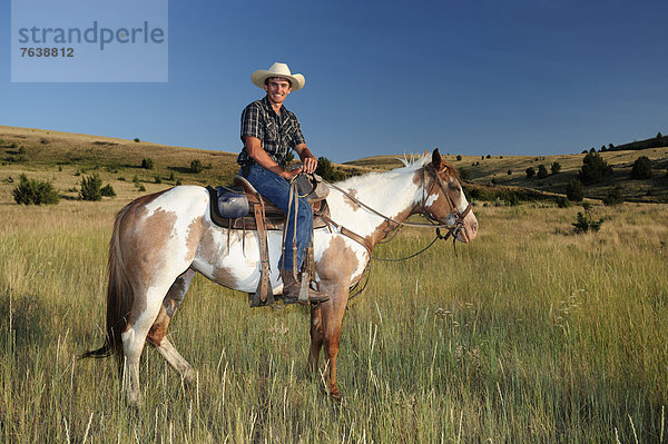Vereinigte Staaten von Amerika  USA  Mann  Sport  Pose  Freundschaft  Amerika  lächeln  Hut  grün  reiten - Pferd  Gras  Cowboy  Oregon  Ranch