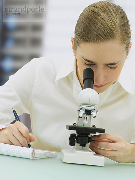 Wissenschaftlerin schaut durch Mikroskop