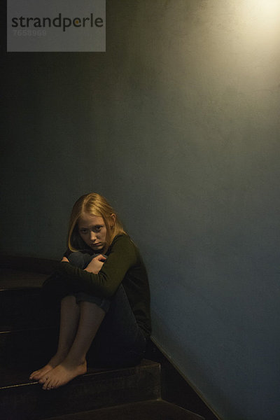 Junge Frau auf der Treppe sitzend  Knie umarmend
