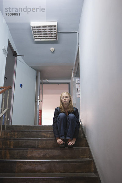 Junge Frau allein auf der Treppe sitzend