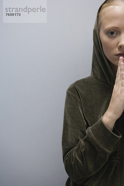 Junge Frau mit im Gebet umklammerten Händen  abgeschnitten