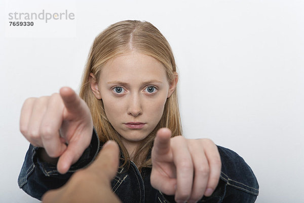 Junge Frau  die mit den Fingern auf eine Person im Vordergrund zeigt.