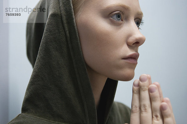 Junge Frau mit im Gebet umklammerten Händen  Porträt