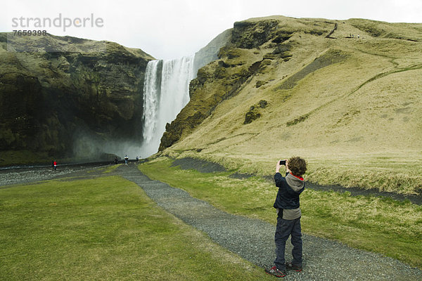 Junge fotografiert einen Wasserfall  Island