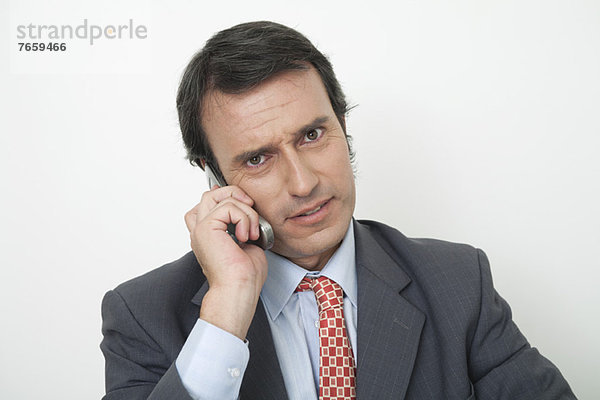 Reife Geschäftsleute sprechen am Handy mit besorgtem Blick