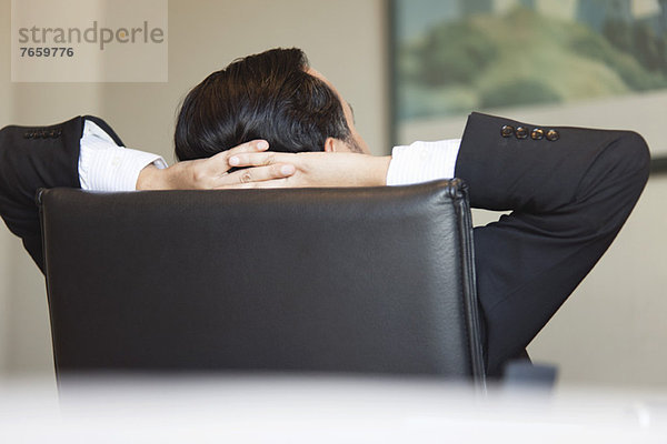 Business Executive entspannt im Bürostuhl mit den Händen hinter dem Kopf