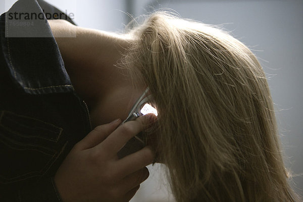 Junge Frau  die beim Telefonieren Haare wirft