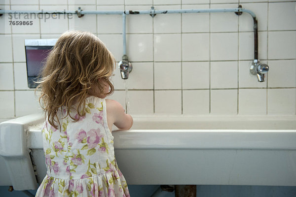 Kleines Mädchen beim Händewaschen im Bad  Rückansicht