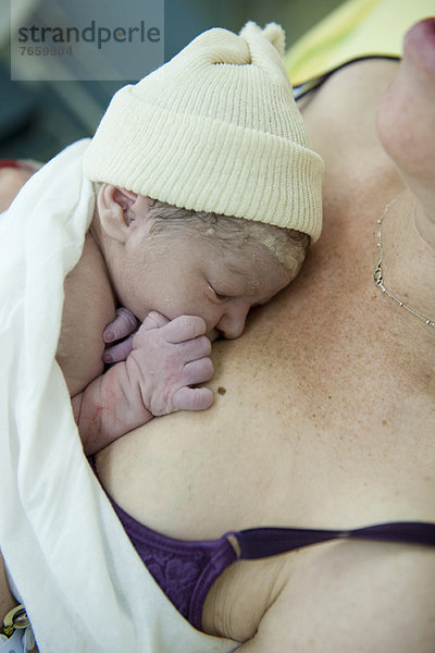 Neugeborenes Baby auf der Brust der Mutter liegend