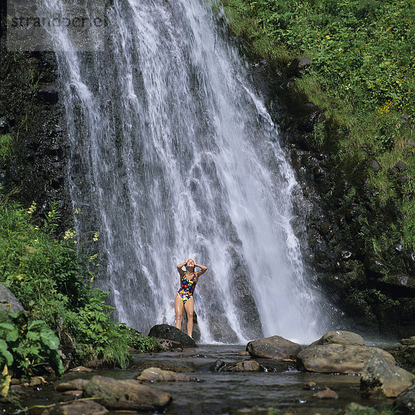 Mädchen badet in einem Wasserfall  Parc Naturel RÈgional des Volcans d'Auvergne  Regionaler Naturpark Volcans d'Auvergne  Puy de Dome  Auvergne  Frankreich  Europa