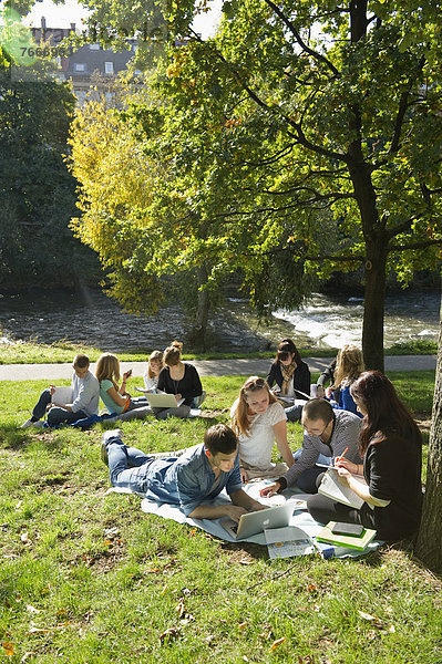 Studenten mit Laptops und Büchern auf einer Wiese  Freiburg im Breisgau  Baden-Württemberg  Deutschland  Europa