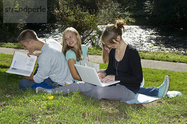 Studenten mit Laptop und Buch auf einer Wiese  Freiburg im Breisgau  Baden-Württemberg  Deutschland  Europa