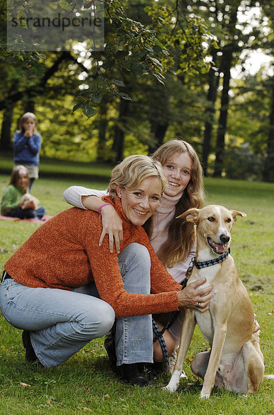 Mutter und drei Töchter mit Hund im Park