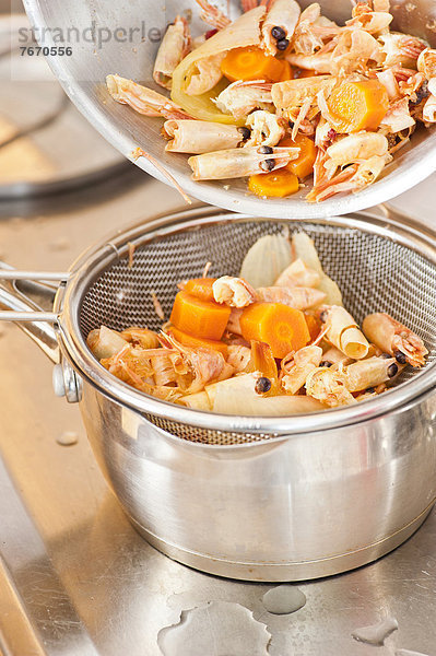 Gekochte Garnelen  Zwiebeln und Karotten tropfen im Sieb ab  Sieb und Topf