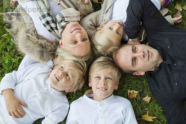 Familie mit drei Kindern liegt im Gras