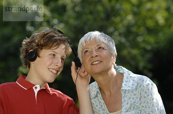 Oma und Enkel hören zusammen an einem Kopfhörer Musik