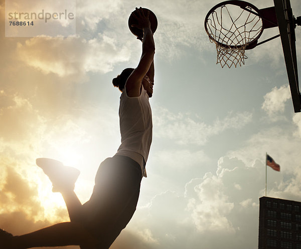 Mann taucht Basketball auf dem Platz ein