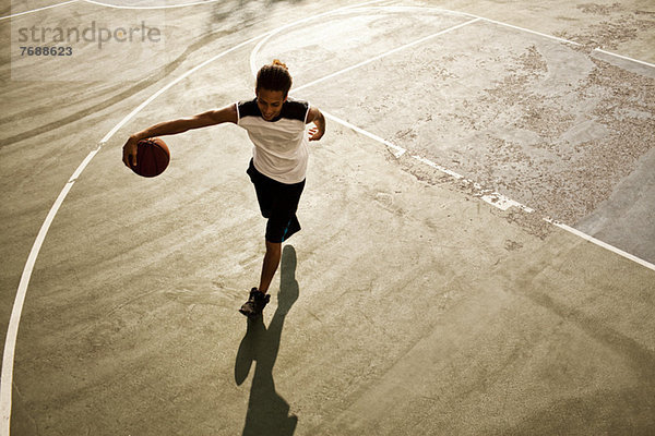 Mann spielt Basketball auf dem Platz