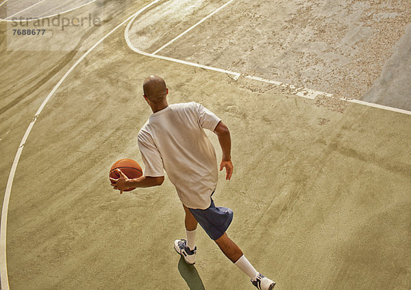 Mann spielt Basketball auf dem Platz