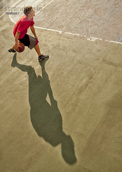 Mann spielt Basketball auf dem Platz