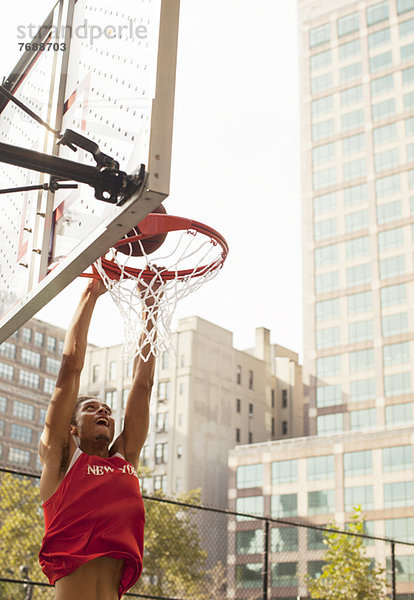 Mann taucht Basketball auf dem Platz ein