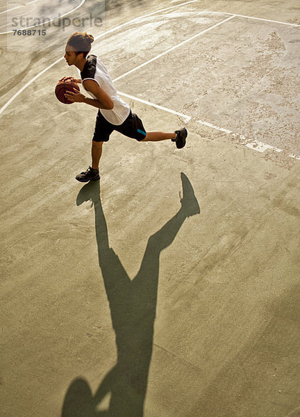 Mann spielt Basketball auf dem Platz