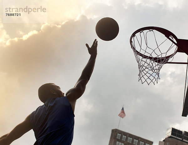 Mann spielt Basketball auf dem Platz