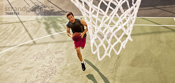 Mann spielt Basketball auf dem Platz