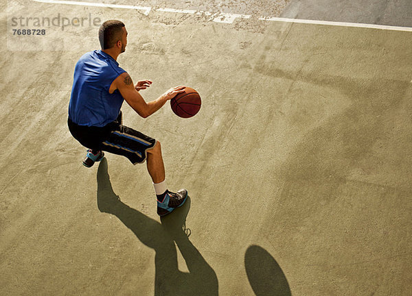 Mann spielt Basketball auf dem Platz