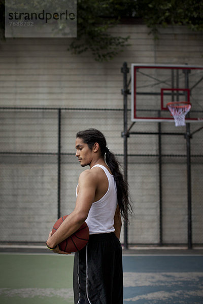 Mann steht auf dem Basketballplatz