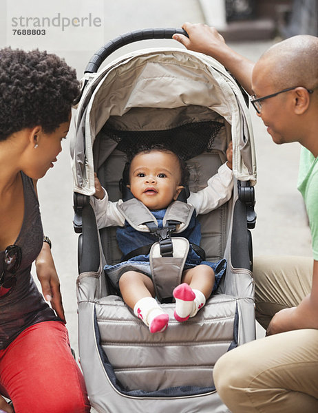 Eltern mit Baby im Kinderwagen auf der Stadtstraße