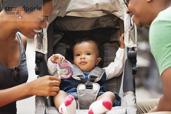 Eltern im Gespräch mit dem Baby im Kinderwagen auf der City Street