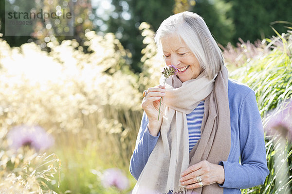 Ältere Frau riecht Blumen im Freien
