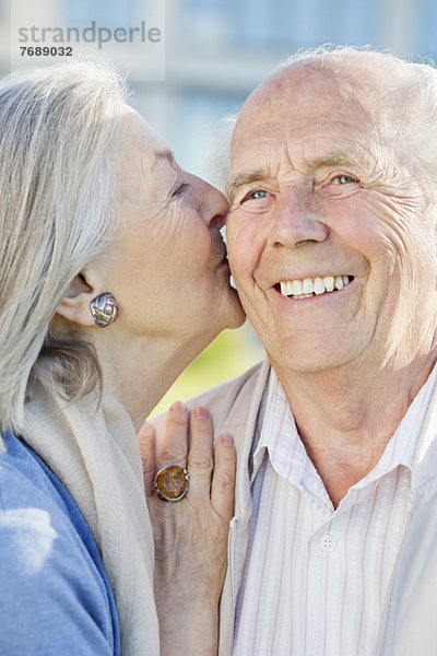 Lächelndes älteres Paar  das sich im Freien küsst.