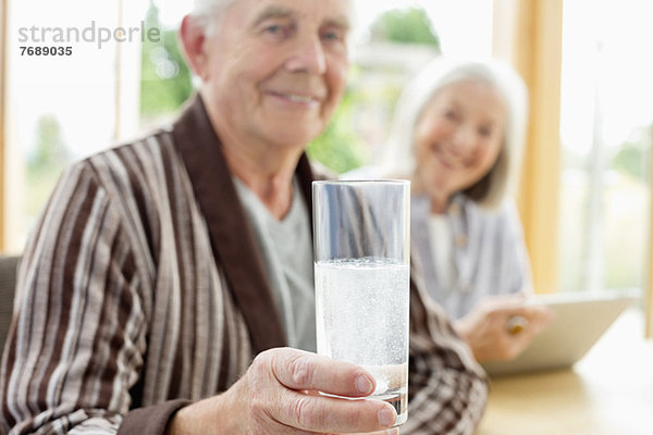 Älterer Mann  der Medikamente im Wasser einnimmt