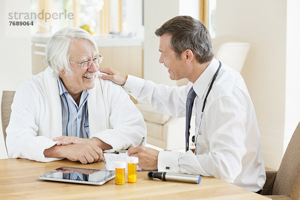 Arzt im Gespräch mit älteren Patienten beim Hausbesuch