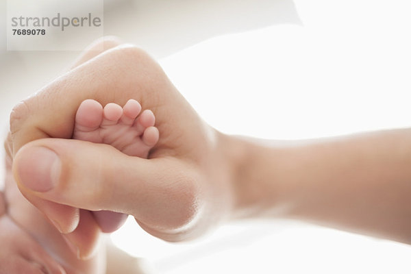 Mutter wiegt den Fuß des Neugeborenen