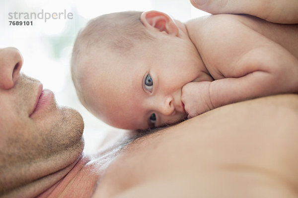 Vater wiegt Neugeborenes auf der Brust