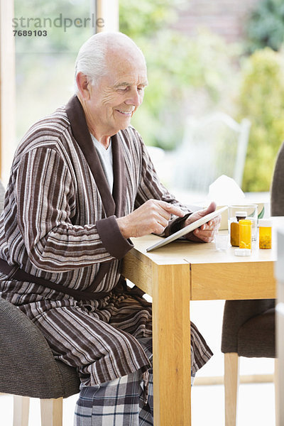 Älterer Mann mit Tablet-Computer am Tisch