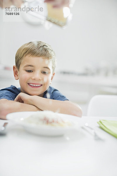 Lächelnder Junge mit Spaghetti am Tisch