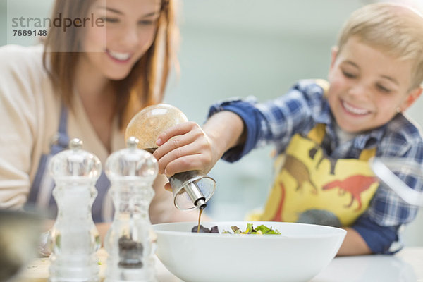 Mutter und Sohn machen Salat in der Küche