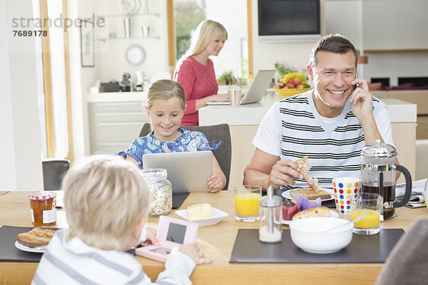 Familie mit Technik beim Frühstück