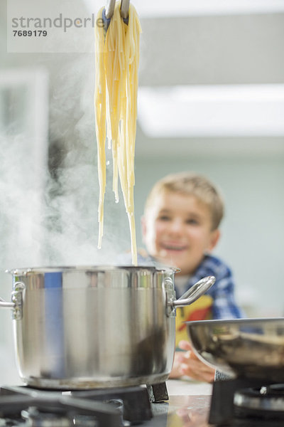 Junge beobachtende Eltern kochen Spaghetti