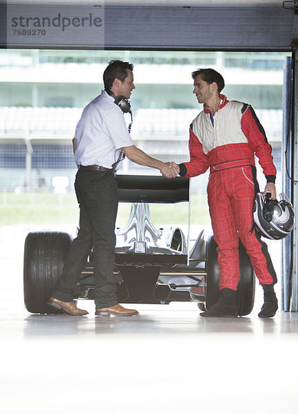 Rennfahrer und Manager beim Händeschütteln in der Garage