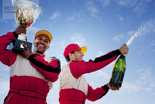 Rennfahrer mit Trophäe und Champagner