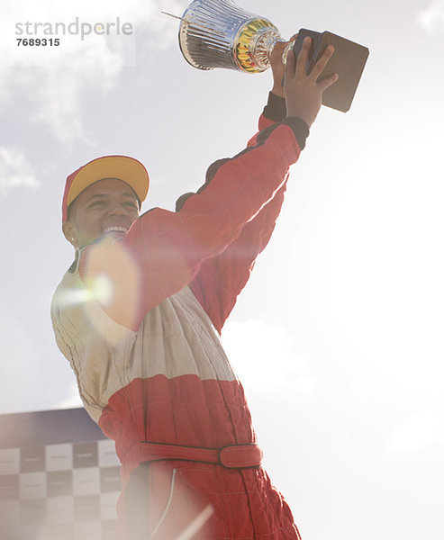 Rennfahrer mit Trophäe bei der Siegerehrung