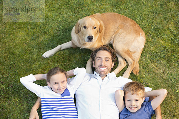 Familie entspannt mit Hund auf dem Rasen