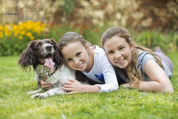 Lächelnde Mädchen entspannen mit Hund auf dem Rasen